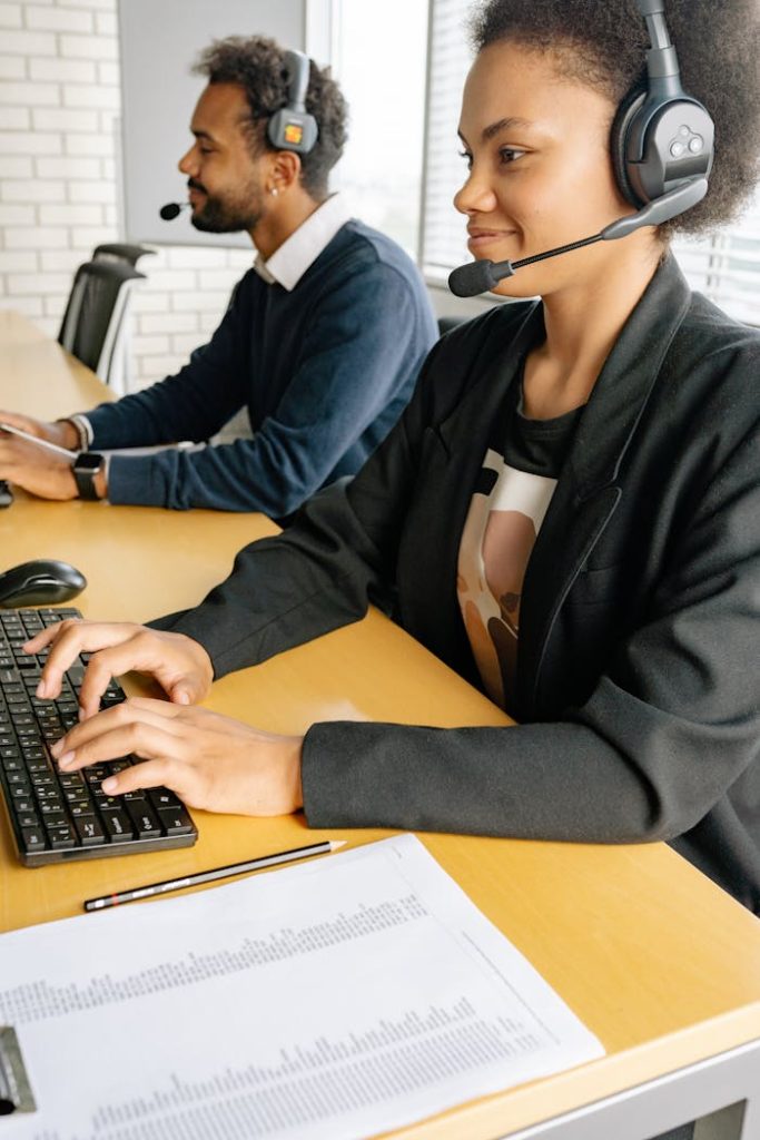 Smiling professionals in a call center working with headsets and computers.